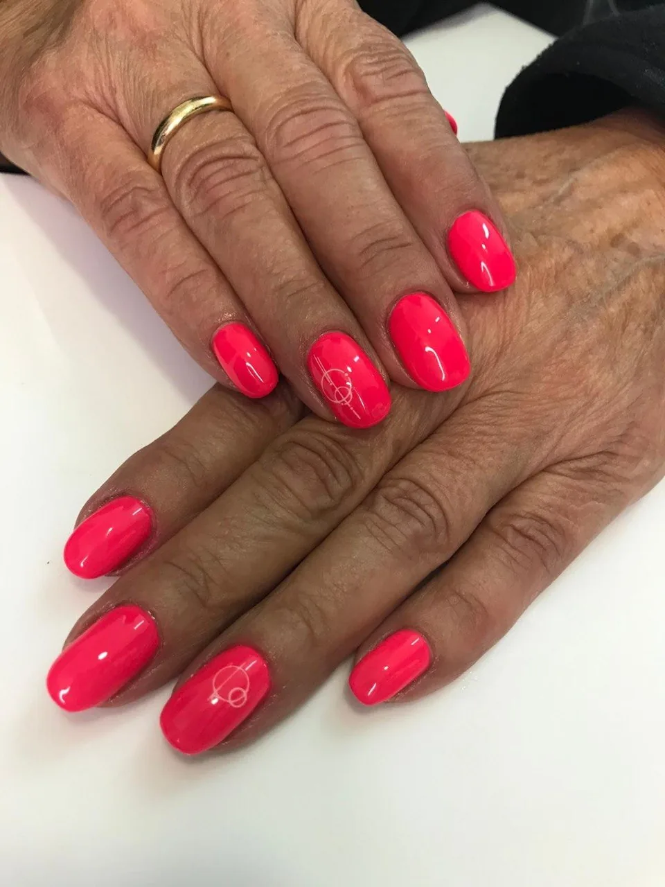 Uñas coral neón con diseño geométrico de líneas