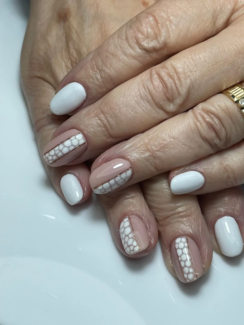 Manicura nude y blanca con diseño de piel de reptil y línea dorada
